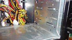 Figure 3. Notice the back of the drive cage where there are three plastic, triangular stops. These slide out of the way to allow mounting screws on the side of units that fit into the cage. Figure 3. Notice the back of the drive cage where there are three plastic, triangular stops. These slide out of the way to allow mounting screws on the side of units that fit into the cage.