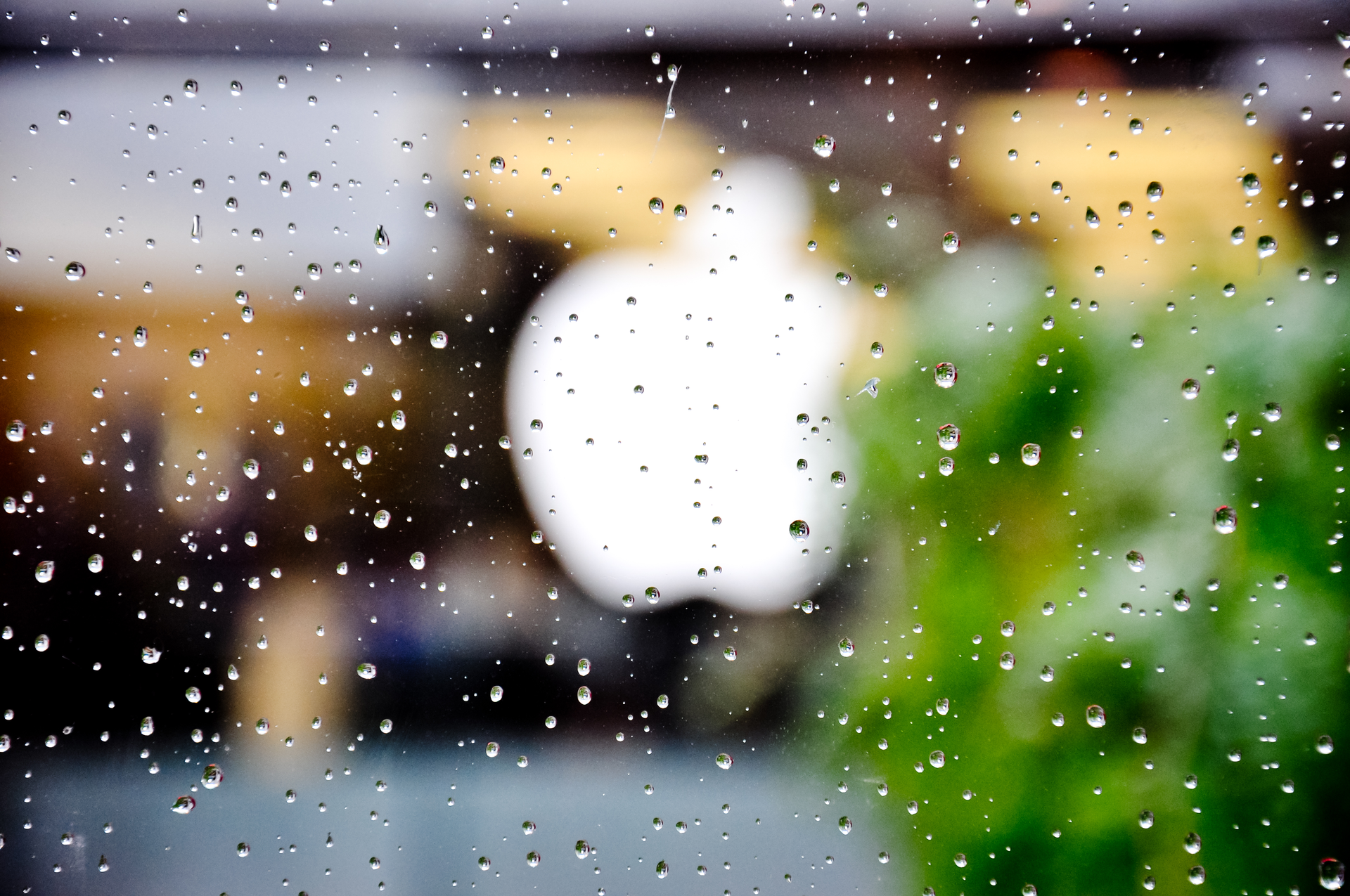 透过雨点溅起的玻璃看到的苹果标志。(图片由Divya Thakur提供，Flickr)