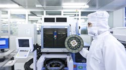 An Infineon Technologies engineer holds a 200 millimeter wafer in a semiconductor cleanroom in Dresden, Germany. (Image courtesy of Infineon).
