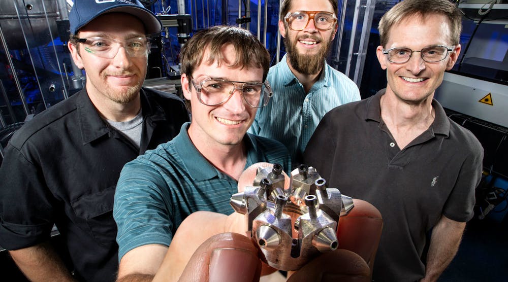 Sandia National Laboratories researchers (left to right: Nathan Harry, Christopher Nilsen, Drummond Biles, and Charles Mueller) show off their prototype of ducted fuel injection module for diesel engines.