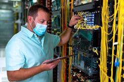 A masked employee checks on the servers. A masked employee checks on the servers.