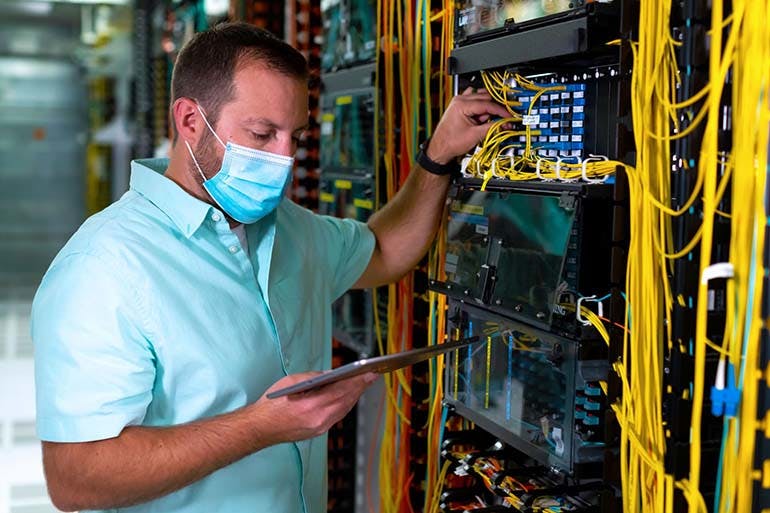 A masked employee checks on the servers.
