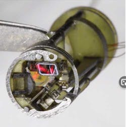 3. The X-Y laser-steering mirrors are driven by MEMS-based flexures; one mirror is clearly visible at the top due to the red laser glow. (Source: Wyss Institute/Harvard University) 3. The X-Y laser-steering mirrors are driven by MEMS-based flexures; one mirror is clearly visible at the top due to the red laser glow. (Source: Wyss Institute/Harvard University)