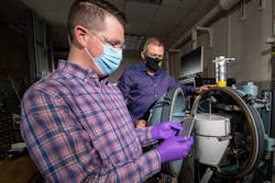 Alex Bates (front) and John Hewson, Sandia National Laboratories engineers, examine a lithium-ion battery in front of a specially designed battery testing chamber.